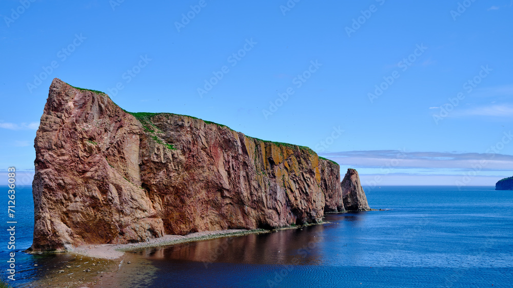 The beautiful colors, natural arch and shape of famous Perce Rock on the Gaspe Peninsula in Quebec Canada at sunset with it's red-pinkish colors from the shores of Perce Village