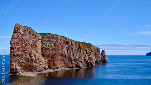 The beautiful colors, natural arch and shape of famous Perce Rock on the Gaspe Peninsula in Quebec Canada at sunset with it's red-pinkish colors from the shores of Perce Village