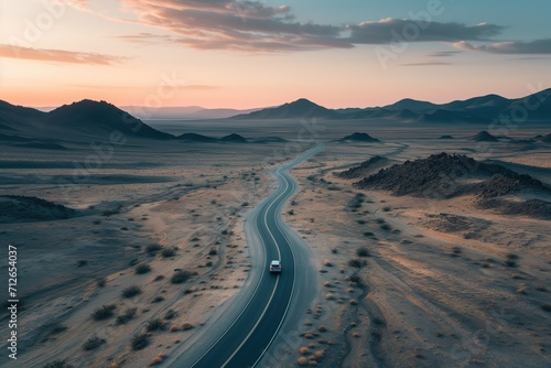 Car driving on winding desert road at sunset