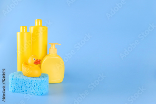 Fotografie Yellow empty mock-ups of shampoo bottles and a yellow rubber duck on a blue sponge