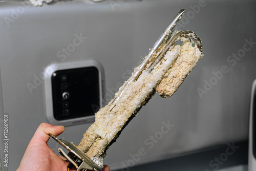 Heating element of an electric water heater with a rusty anode and a tube covered with scale