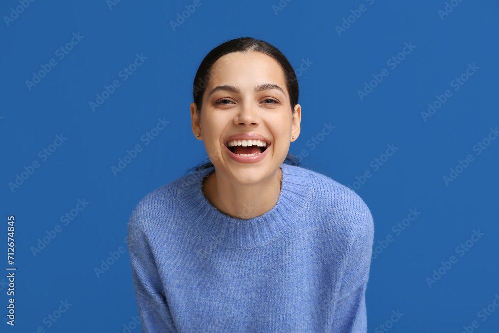 Beautiful young happy woman laughing on blue background Beautiful young happy woman laughing on blue background