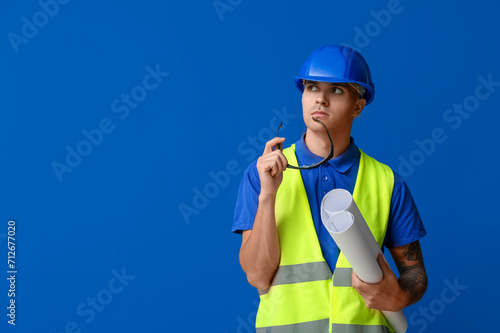 Young male engineer with blueprint on blue background