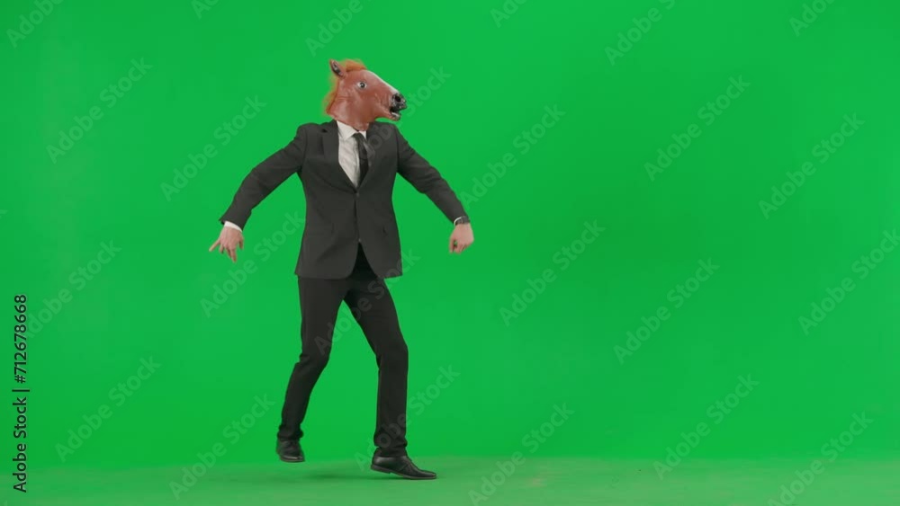 A man in a business suit with a horse head mask on a green studio background. A businessman appears in the frame in a comic manner, gallops like a horse and disappears. A man in a business suit with a horse head mask on a green studio background. A businessman appears in the frame in a comic manner, gallops like a horse and disappears.