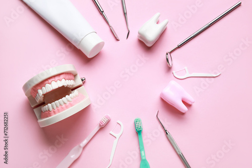 Frame made from dental tools, oral hygiene supplies and plastic models on pink background. World Dentist Day