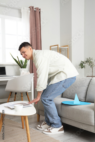 Young man with hemorrhoids and paper thumbtack on sofa at home