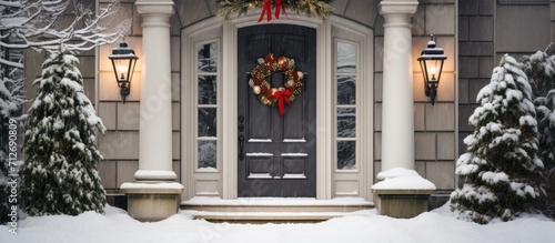 House door with holiday wreath and snowy bushes photo