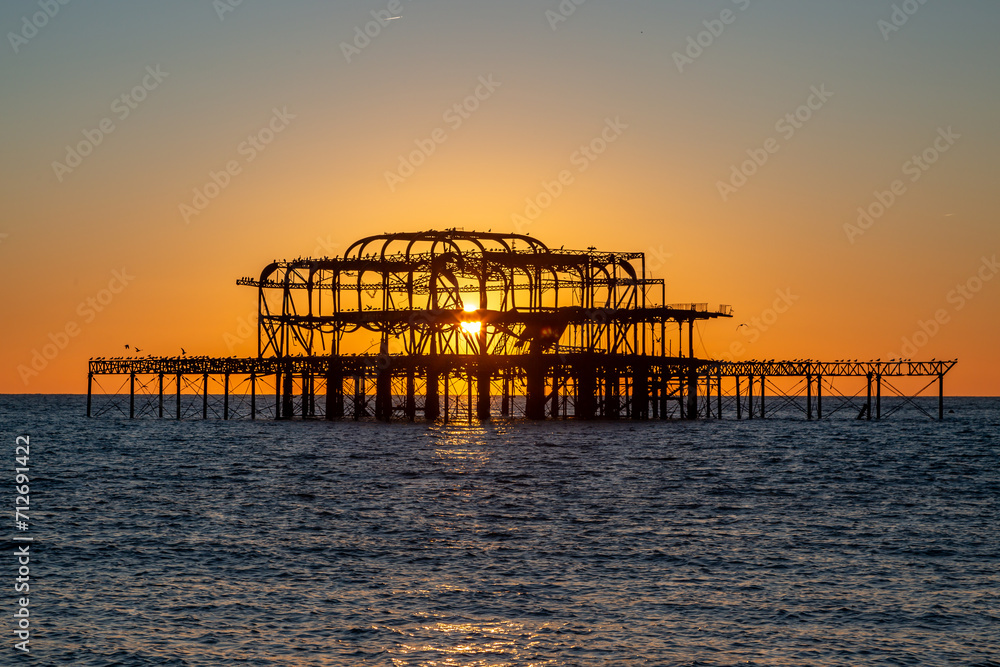 The sun setting behind the old West Pier in Brighton, on a winter's evening