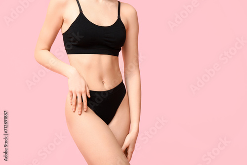 Beautiful young woman in black cotton underwear on pink background