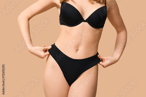 Attractive young woman in black underwear on beige background, closeup