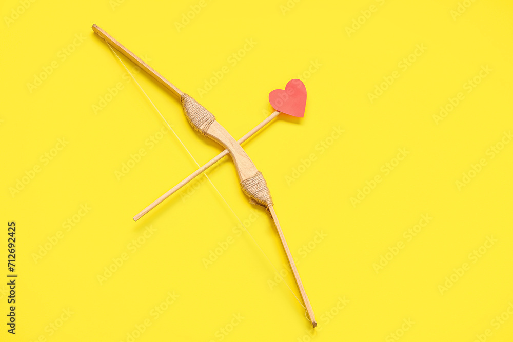 Paper heart with arrow and bow on yellow background. Valentine's day celebration Paper heart with arrow and bow on yellow background. Valentine's day celebration