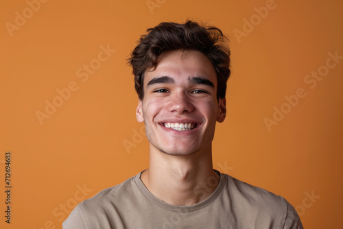 A young man is smiling with an orange background