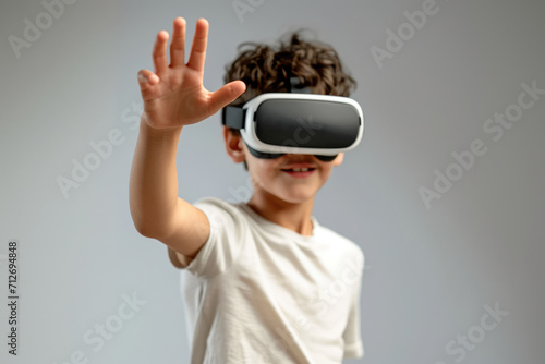 A young boy wearing a virtual reality headset reaches out his hand