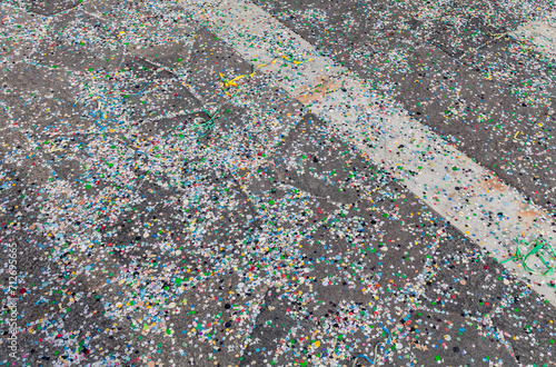 Confetti of different colors and strips of paper stuck on the asphalt after the carnival celebrations