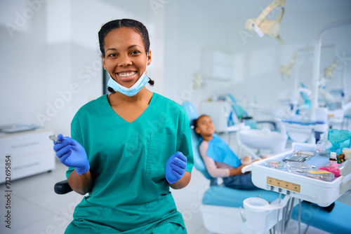 Happy black female dentist at work looking at camera.