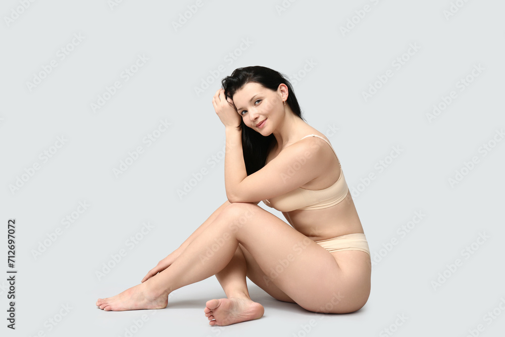 Body positive young woman in underwear sitting on light background Body positive young woman in underwear sitting on light background