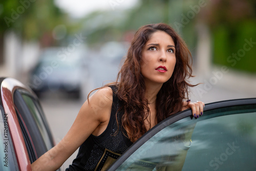 Bild auf Leinwand Mujer joven abriendo la puerta de su coche mirando con asombro lo que está pasan