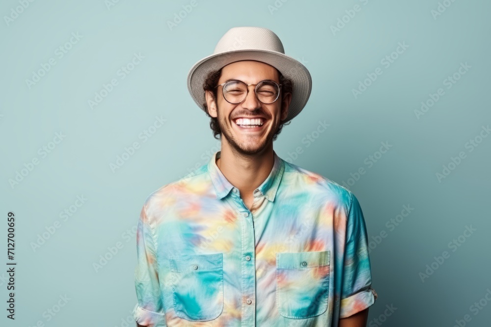 Portrait of a happy young man in hat and glasses over blue background