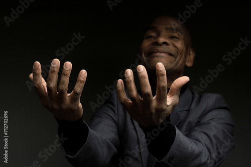 praying to god Caribbean man praying with black background with people stock photo	