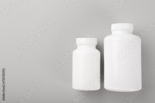 Blank white pill bottles on light grey background, top view. Space for text