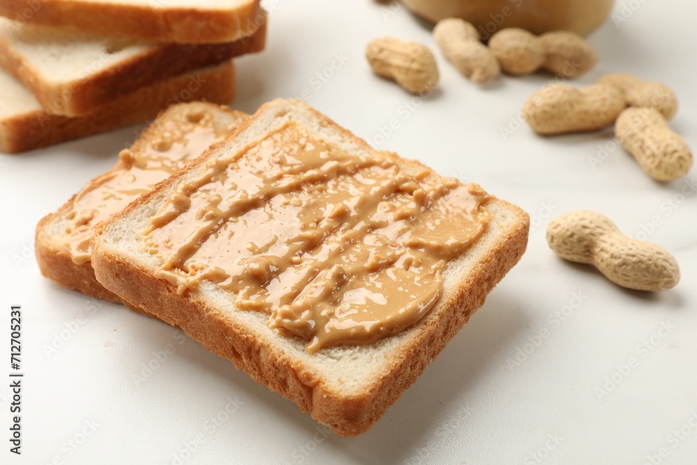 Delicious toasts with peanut butter and nuts on white table, closeup Delicious toasts with peanut butter and nuts on white table, closeup