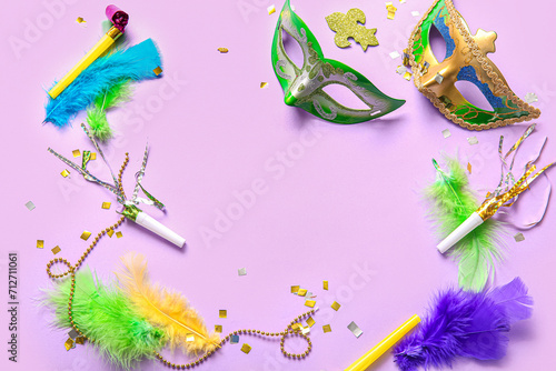 Frame made of carnival masks with party horns and decor for Mardi Gras celebration on lilac background