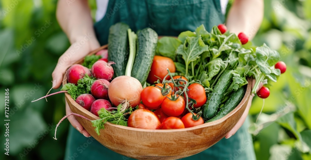 Fototapeta premium a woman has a wooden bowl filled up with fresh vegetables
