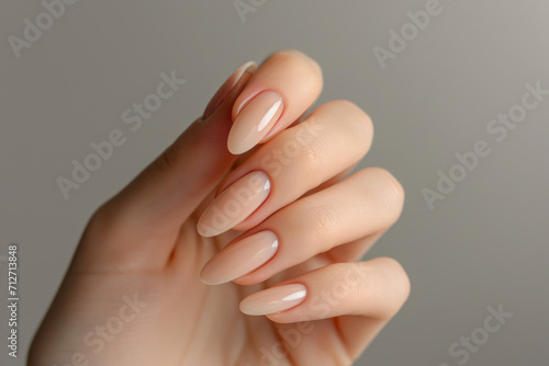 Closeup to woman hands with elegant neutral colors manicure. Beautiful nude manicure on long almond shaped nails. Nude shade nail manicure with gel polish at luxury beauty salon photo