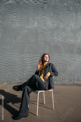 A person sitting on a chair outdoors, with a wall and the ground in the background 5589.