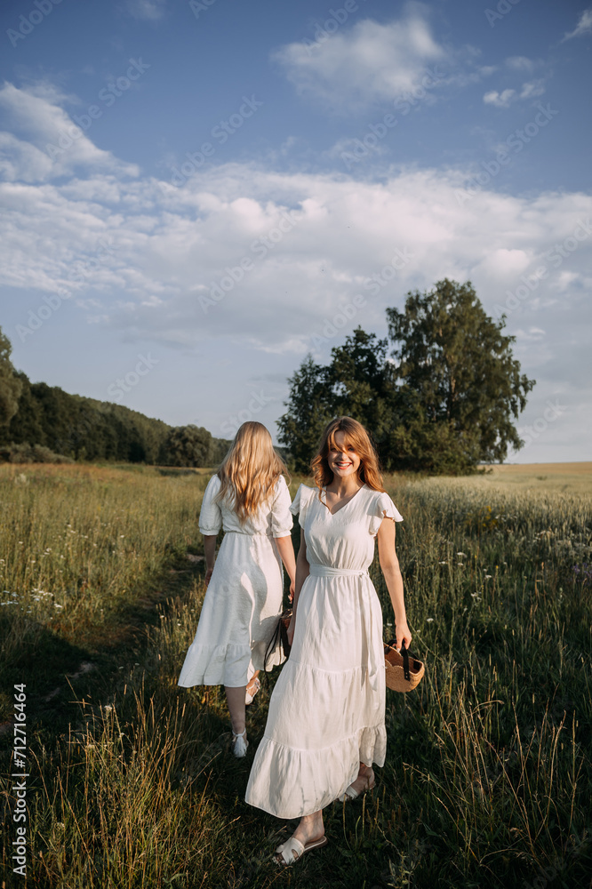 The image features two women in white dresses standing in a field of tall grass under a cloudy sky 5634. The image features two women in white dresses standing in a field of tall grass under a cloudy sky 5634.