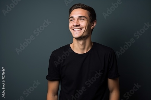 Portrait of a handsome young man laughing against a dark background.