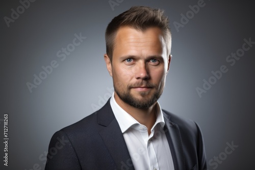 Portrait of a young handsome man in a suit on a gray background © Inigo