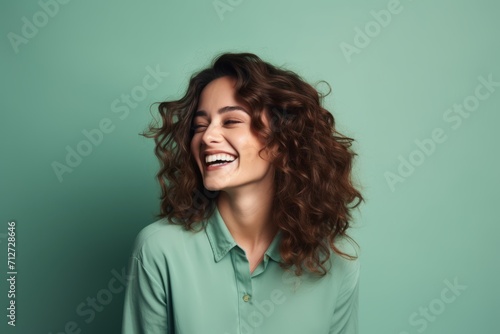 Portrait of a happy young woman with long curly hair on a green background