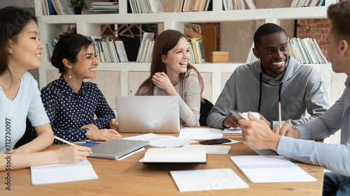 Bilde på lerret Overjoyed multiracial young people sit at table with laptop and paperwork have f