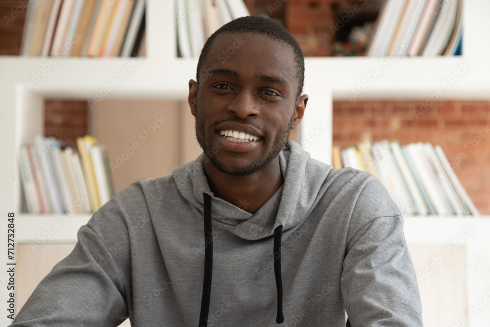 Smiling african American millennial guy look at camera having video call indoors, biracial ethnic young male tutor or coach talk on cam record shoot online training course or educational webinar Smiling african American millennial guy look at camera having video call indoors, biracial ethnic young male tutor or coach talk on cam record shoot online training course or educational webinar