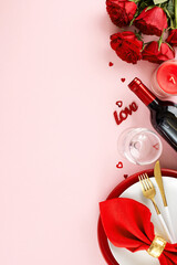 Sweet rendezvous: savoring Valentine's day magic. Top view vertical flat lay of plates, cutlery, hearts, candle, red roses, wine bottle, wine glass on pastel pink background with advert zone