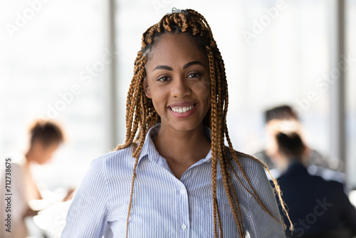 Profile picture portrait of attractive young black lady hipster office team leader member looking at camera with confidence. Pleasant millennial woman skilled business trainer coach pose at workplace photo