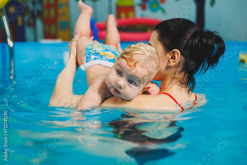 Swimming pool for training newborn children to swim. Baby swimming in the pool. Teaching a newborn boy to swim in a pool with a coach © Дмитрий Ткачук