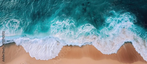 Bird's-eye perspective of ocean waves lapping a secluded sandy coast.