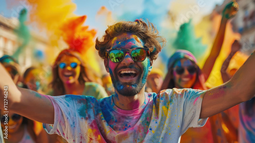 Happy people celebrating Holi festival, smiling man stained paint on colorful powder. Portrait of youth having fun. Concept of color, party, holiday, travel, India