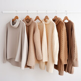 Women's clothes capsule wardrobe in pastel colors. Knitted jumpers and cardigans for spring autumn season on hanger in store against light wall