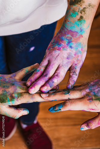 children putting paint-stained hands together, children having fun with paint, children playing with colorful paint