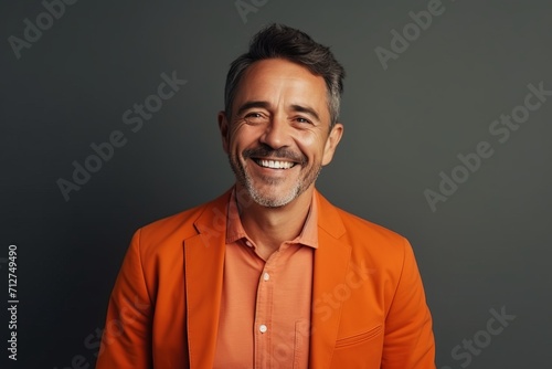 Portrait of a smiling middle-aged man in an orange jacket. © Inigo