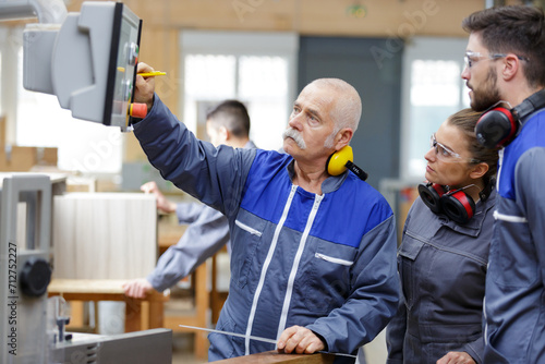 engineer and apprentices working on machine in factory