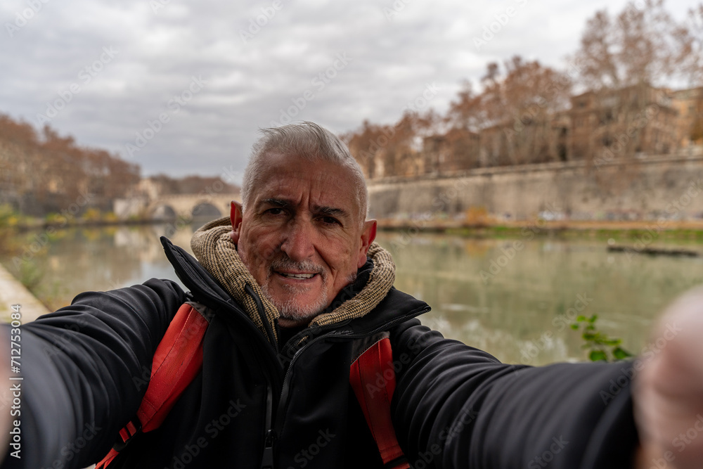 happy middle aged man on vacation taking a selfie on the banks of the Tiber river in rome happy middle aged man on vacation taking a selfie on the banks of the Tiber river in rome