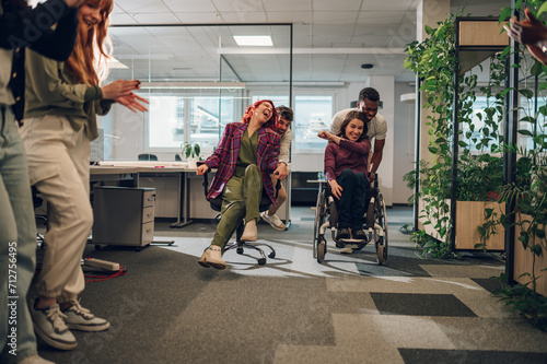 Hispanic woman and a woman with disability participating in an office chair race photo