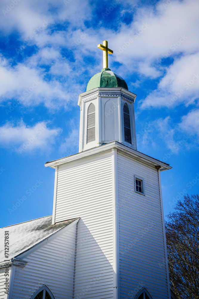 Chapel with golden cross and the blue sky with white clouds, close-up