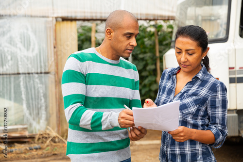 Delivery courier invites the farmer to sign documents in the courtyard of country house