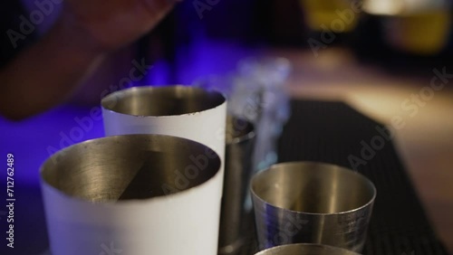 Preparation of alcoholic cocktails. Close-up of a bartender adding ice cubes to a mixing glass behind the bar counter. Close-up of a bartender adding ice to cocktails. The bartender adds ice to cockta photo