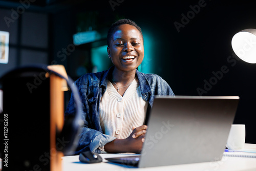 Εκτύπωση καμβά Black woman enjoying a comedy movie on her digital laptop, while seated at desk in her apartment